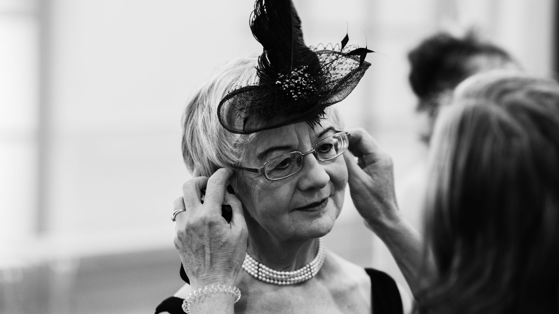 297B&WJOIEDEVIVRE161009Matt Austin A black and white photograph of a woman having her fascinator adjusted by someone off camera.