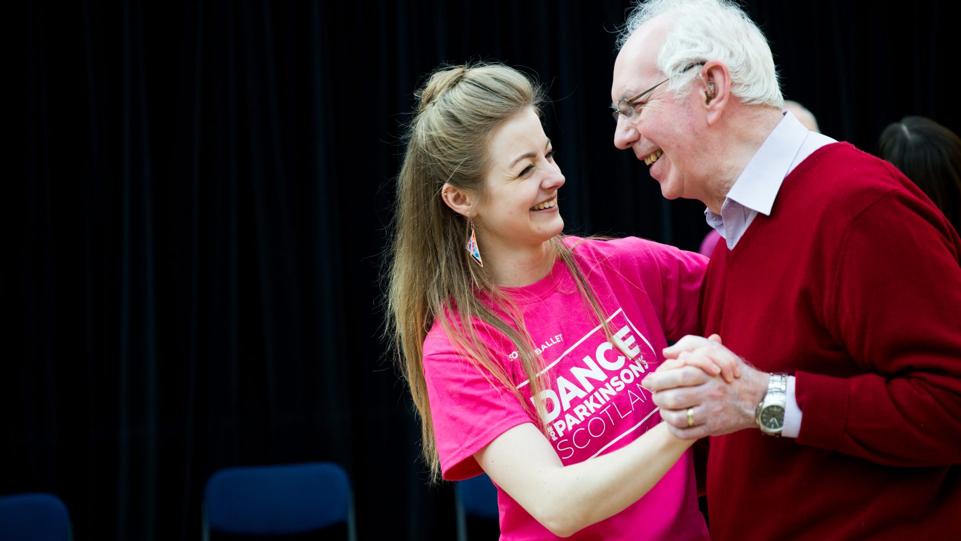 danceparkinsons-86 A man and woman are dancing together in a partner hold. They are smiling at each other.