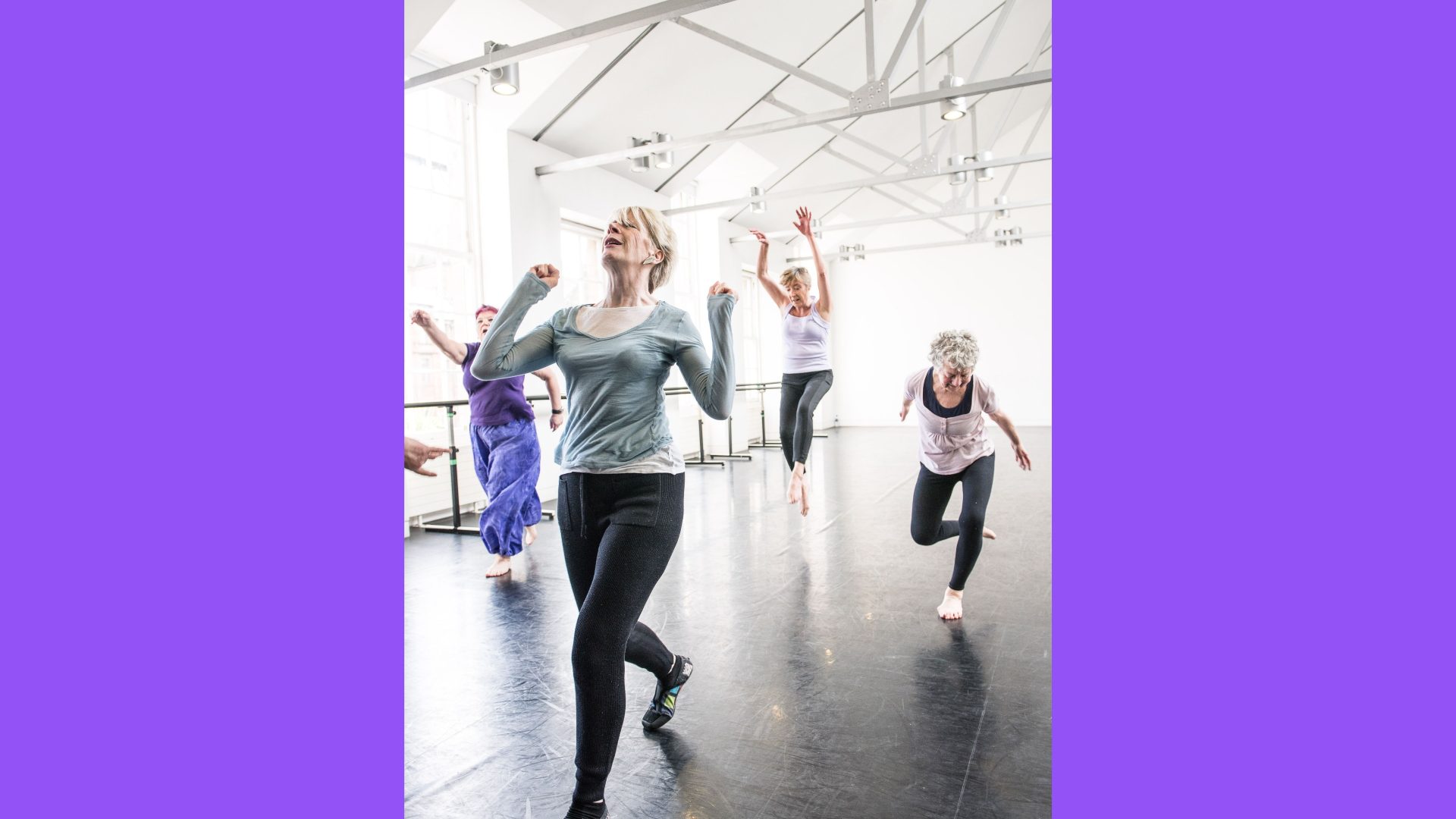 PRIME, rehearsal for ‘TARN’ by Angus Balbirnie, 2015. Photograph by Brian Hartley. A group of women are dancing energetically in a dance studio. One has her arms and head thrown back. Another is mid-jump with her arms high. The others are in motion and appear to be reaching.