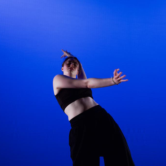 Islay Spanswick A photograph of a dancer, shot from below, against a blue background