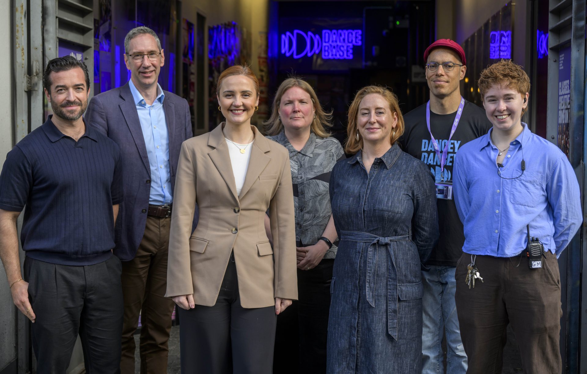[Image: a group photograph outside the entrance to Dance Base. From left to right: Marc Cairns (Associate Director Scottish Futures Trust), Peter Reekie (CEO Scottish Futures Trust), Màiri McAllan MSP (Cabinet Secretary for Education, Culture and Gaelic), Karen Ridgewell (Climate Emergency and Sustainability Lead, Creative Scotland), Jeanie Scott (CEO, Dance Base), Tony Mills (Artistic Director, Dance Base), Han Joyce (General Manager, Dance Base).]